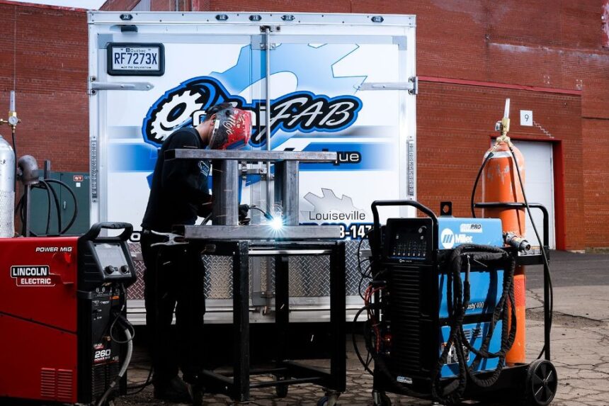 Omnifab mobile welding technician performing on-site welding work with industrial equipment in front of a service trailer